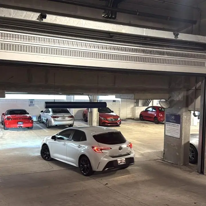 A wide steel roll-up door on a commercial parking structure, part raised