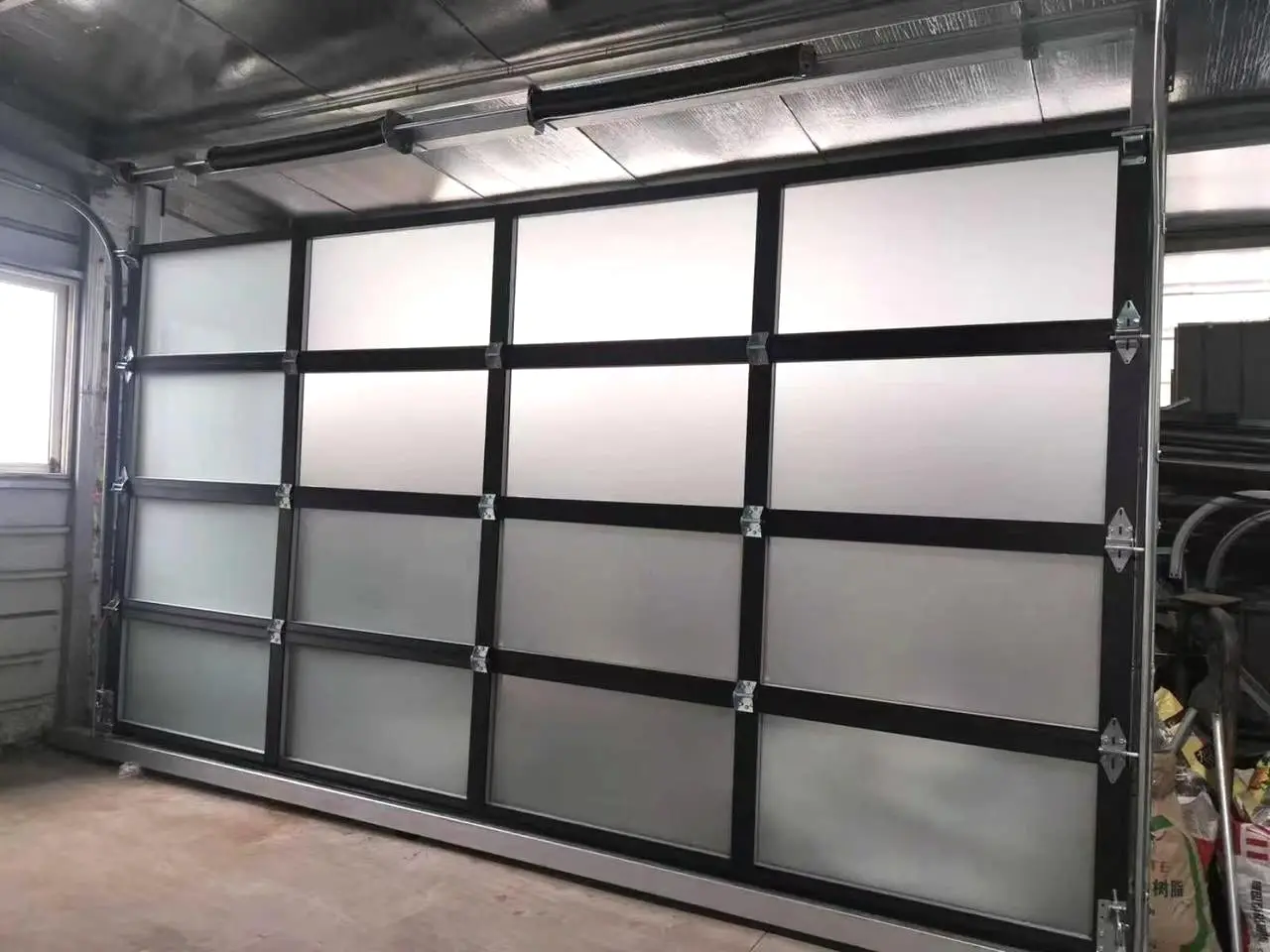 A newly fitted full-view garage door with black aluminium framing and frosted glass panels